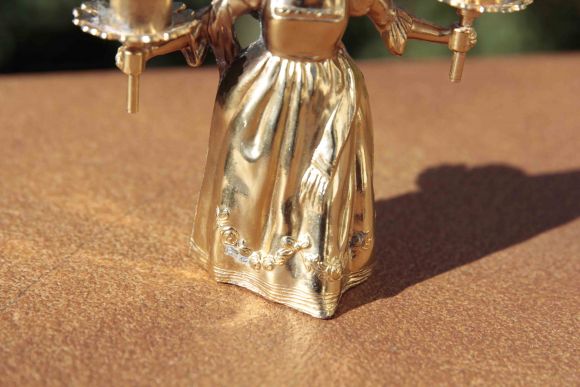 Старинный отполированный подсвечник в виде молодой девушки